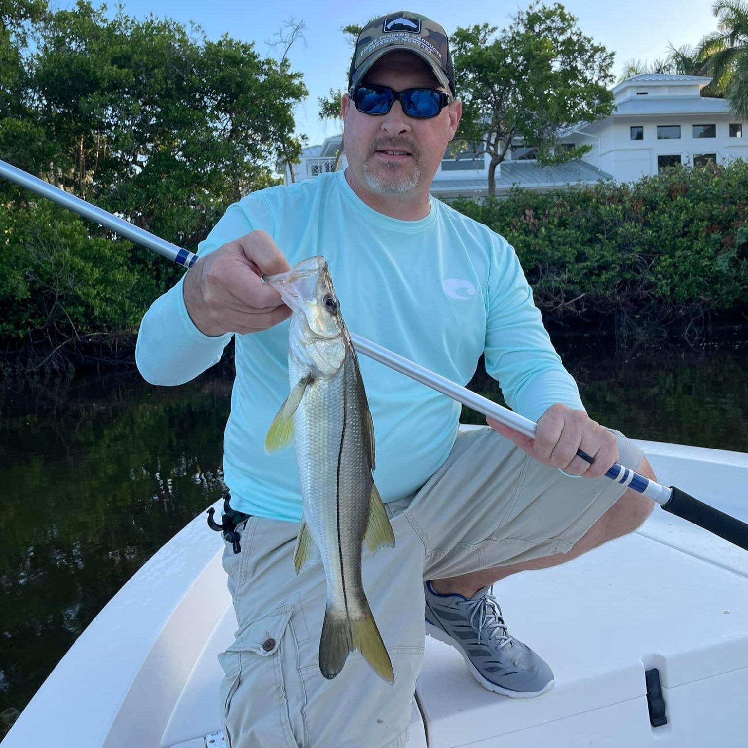 Angler holding a snook caught using the Wasatch Tenkara Rods Open Waters rod, fishing from a boat inshore near mangroves.