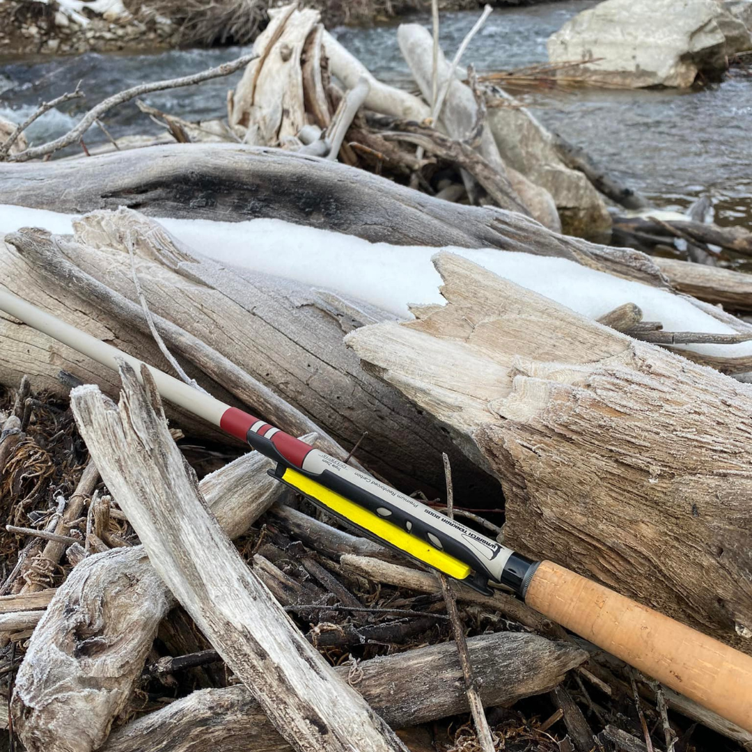 The T-Hunter is a strong and versatile triple zoom tenkara rod. In this photo it is laying on logs that are covered in snow.